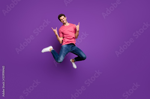 Full size photo of cheerful crazy guy heavy metal music concert lover enjoy rejoice jump show horned symbol wear casual style clothes sneakers isolated over bright shine color background © deagreez