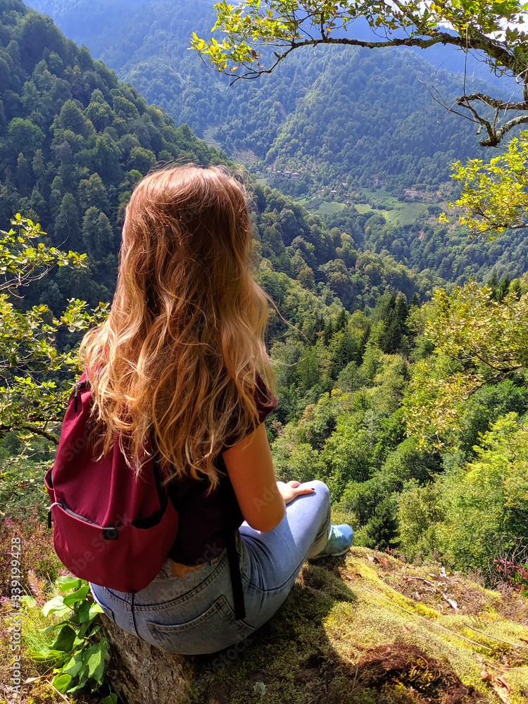 A girl-traveler looks at the mountain valley.