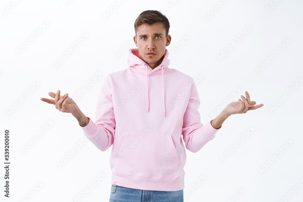 Why, what you want. Portrait of questioned, puzzled blond handsome man, shrugging, spread hands sideways and look confused, cant understand what happening, stand white background Why, what you want. Portrait of questioned, puzzled blond handsome man, shrugging, spread hands sideways and look confused, cant understand what happening, stand white background
