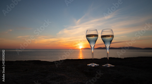 sunset at the ramparts of alghero city with silhouette with two glasses of prosecco