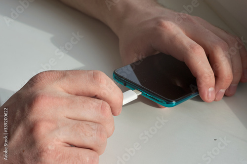Man hands plugging a charger on a smart phone