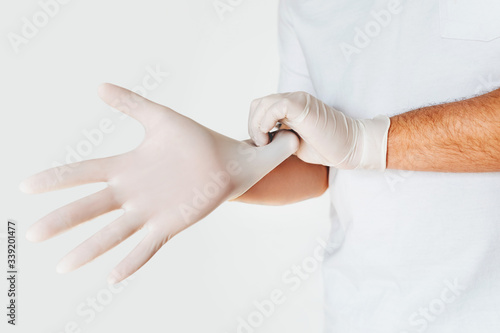 A close-up of man's hands putting on medical protective gloves, on light background. Avoid contaminating Corona virus Covid-19 concept