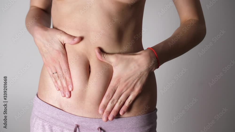 Woman squeezes hands fat on her stomach. Caucasian woman's stomach and arms. Weight Loss During Quarantine. Attractive young woman with bare belly. Woman squeezes hands fat on her stomach. Caucasian woman's stomach and arms. Weight Loss During Quarantine. Attractive young woman with bare belly.