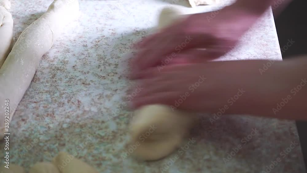 Closeup of kneading dough on kitchen table, side view. Mature woman put sticky dough in flour on table and start kneading it. Closeup of kneading dough on kitchen table, side view. Mature woman put sticky dough in flour on table and start kneading it.