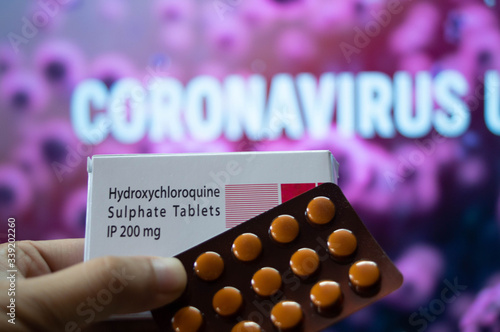 Hydroxychloroquine Sulphate tablets with coronavirus written in background photo