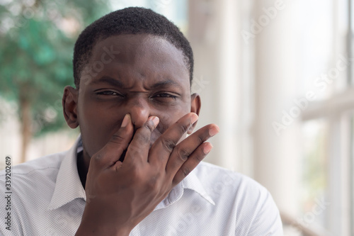 Fotografía African black man covering his nose for bad smell; African black man plugging hi