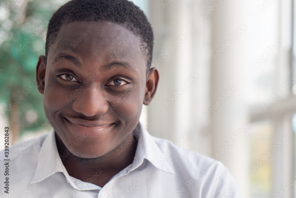 Happy smiling African black man; portrait of optimistic friendly African black man with positive smiling face expression Happy smiling African black man; portrait of optimistic friendly African black man with positive smiling face expression