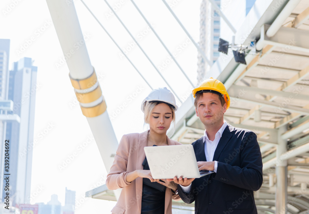A male engineer wearing a helmet and a businesswoman Caucasoid consulted about the Blueprint building. They wanted to build an office in the middle of the city. Business cooperation concept A male engineer wearing a helmet and a businesswoman Caucasoid consulted about the Blueprint building. They wanted to build an office in the middle of the city. Business cooperation concept
