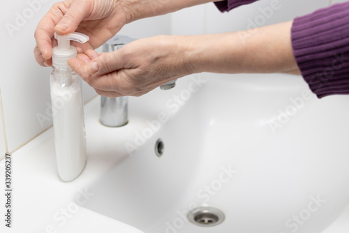 Woman washing her hands with white liquid soap.