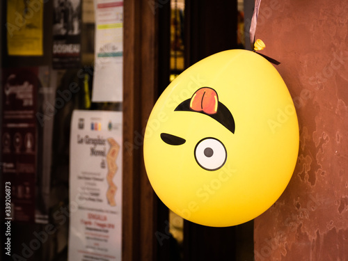 Obraz na płótnie Winking emoji balloon hangs upside down outside a shop in Senigallia, Le Marche, Italy w salonie