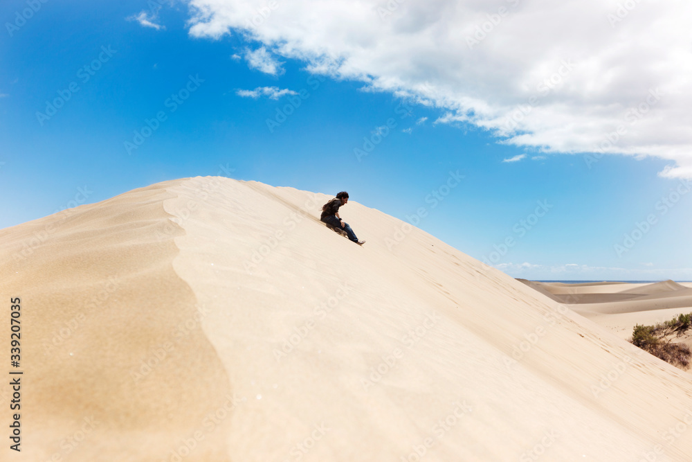 Unrecognizable man slipped on a desert dune. New experiences traveling around the world. Man walking through the dunes in a warm summer day. Travel and holidays concept. Maspalomas natural landscape.