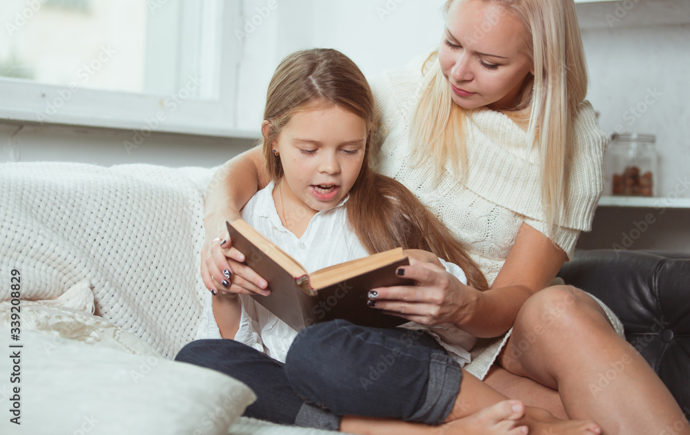 Mom and daughter read a book at home. Mom and daughter read a book at home.