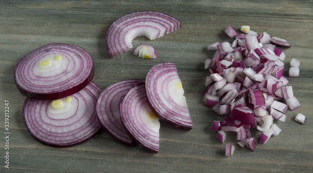 Red onions cut into circles, half-rings and cubes on a dark wooden table