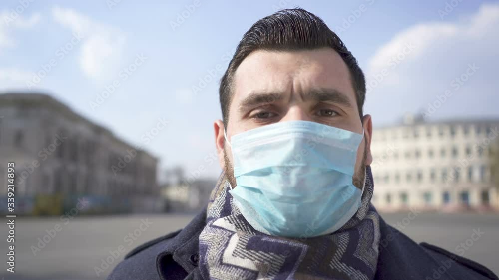 Bearded caucasian man in medical mask on city street. Close up portrait Bearded caucasian man in medical mask on city street. Close up portrait