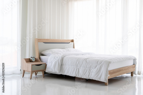 Wooden bed, white mattress, white curtain © suwanb