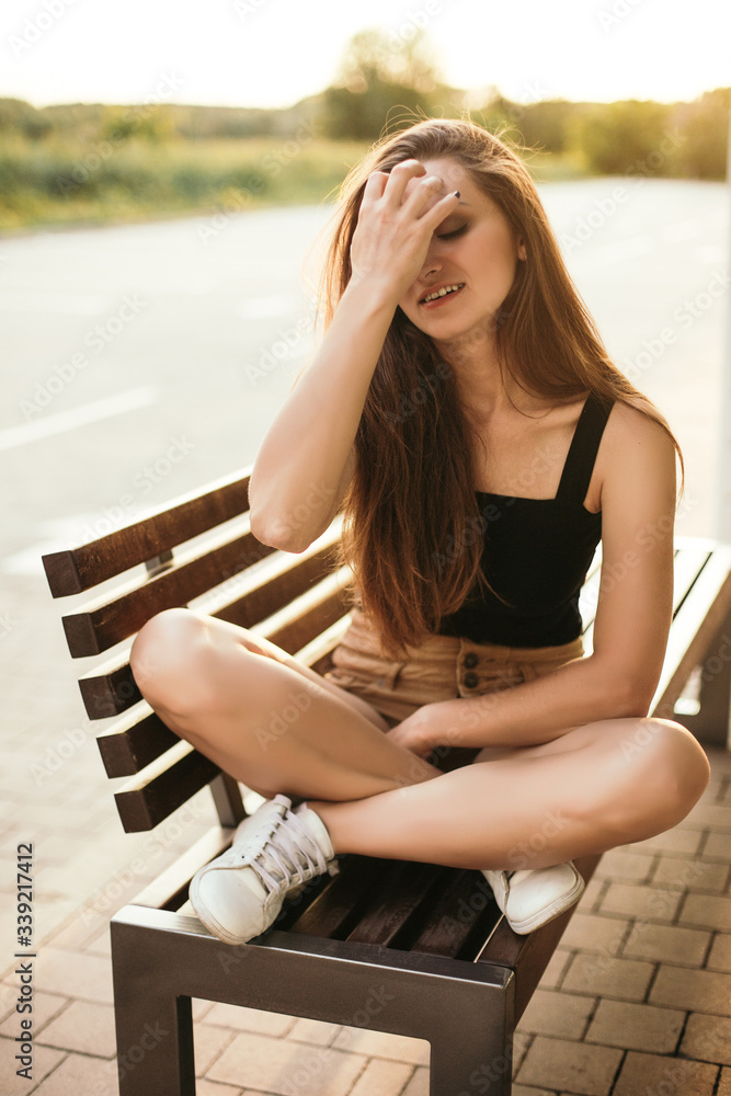 Beautiful young woman posing for the camera sitting on the bench.