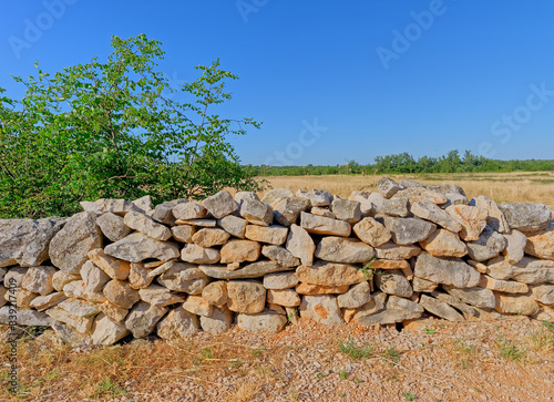 A dirt road in the heart of Dalmatia, bordered by a traditional stone fence, in Promina county in Croatia. Drywall construction is a protected intangible cultural heritage of humanity by UNESCO.