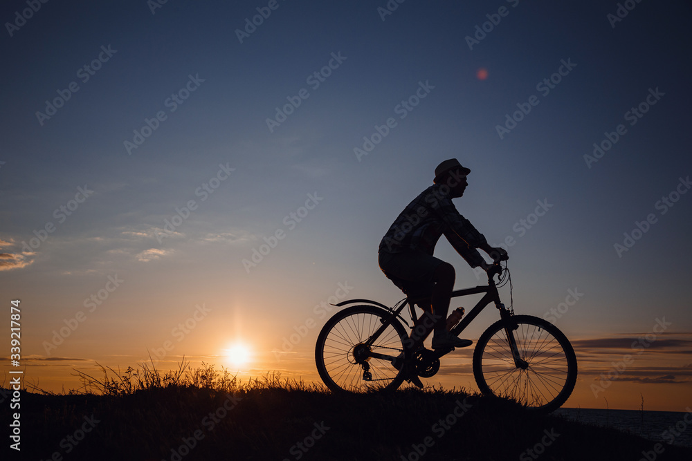 silhouette of a hipster man on a bicycle on sunset background silhouette of a hipster man on a bicycle on sunset background