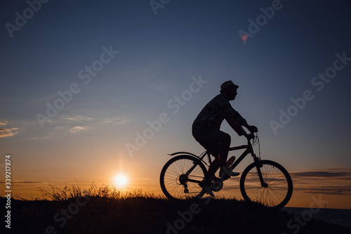 Fototapeta Naklejka Na Ścianę i Meble -  silhouette of a hipster man on a bicycle on sunset background