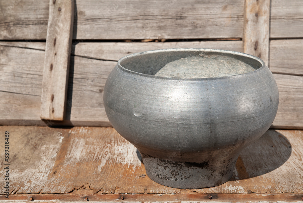 a large cast-iron cauldron of metallic color stands on a wooden background, a pot open a large cast-iron cauldron of metallic color stands on a wooden background, a pot open
