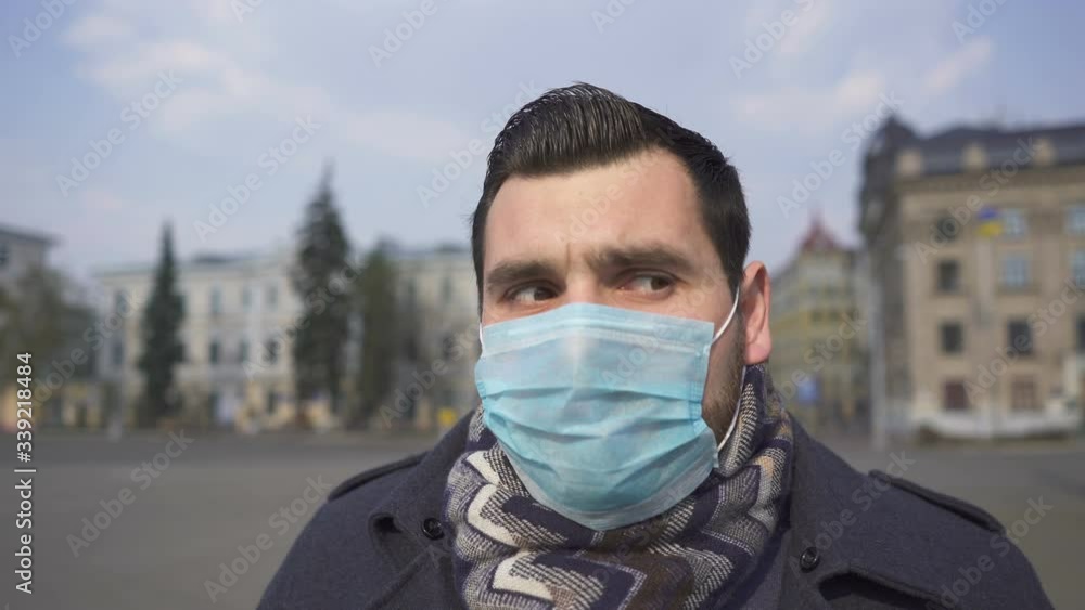 Stylish bearded caucasian man coughs in medical mask on empty city street. Pandemic team Stylish bearded caucasian man coughs in medical mask on empty city street. Pandemic team