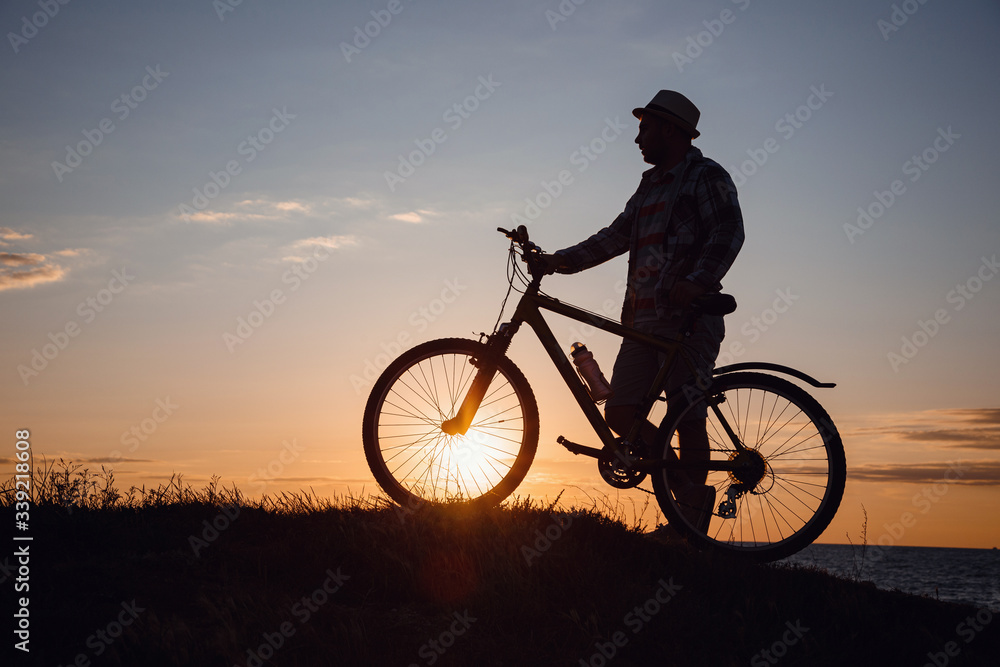 silhouette of a hipster man on a bicycle on sunset background silhouette of a hipster man on a bicycle on sunset background