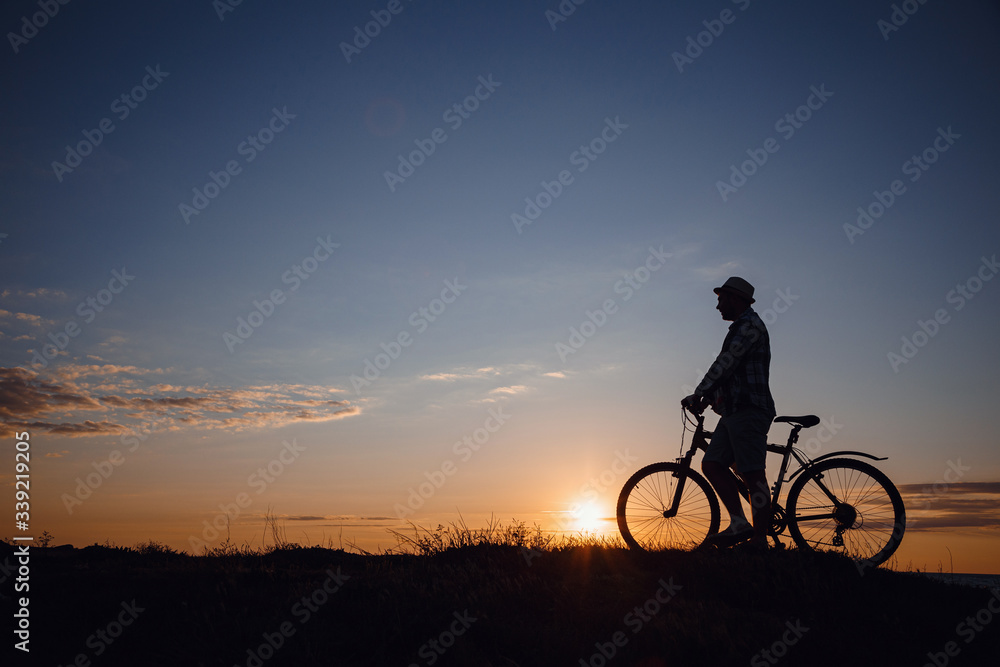 silhouette of a hipster man on a bicycle on sunset background silhouette of a hipster man on a bicycle on sunset background