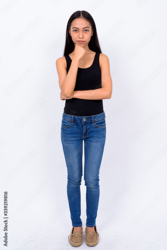Full body shot of young beautiful Asian woman thinking Full body shot of young beautiful Asian woman thinking