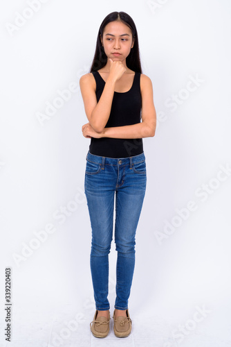 Full body shot of young Asian woman thinking