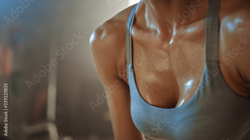 Close Up Shot of a Beautiful Strong Fit Brunette Coverd in Sweat after Intense Fitness Training Workout in a Loft Industrial Gym with Motivational Posters. She's Catching Her Breath.