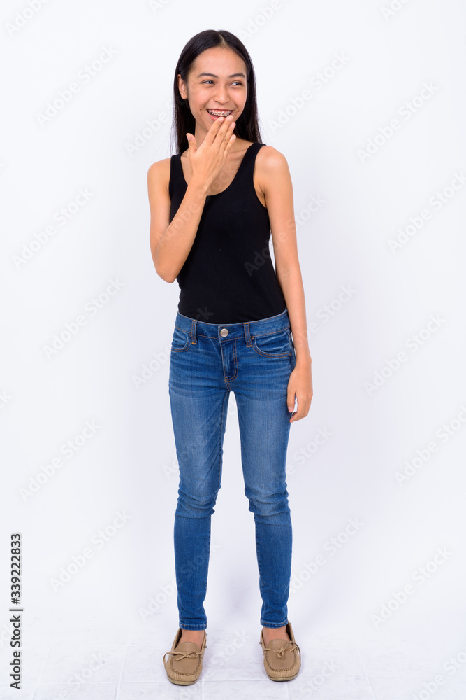 Full body shot of happy young Asian woman laughing Full body shot of happy young Asian woman laughing