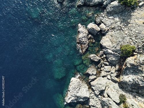 Sharp stones and rocks in the turquoise, blue sea. Drone aerial shot from above with white stone coast. Turkey