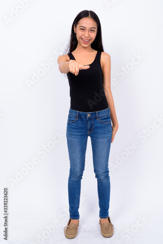 Full body shot of happy young Asian woman pointing at camera