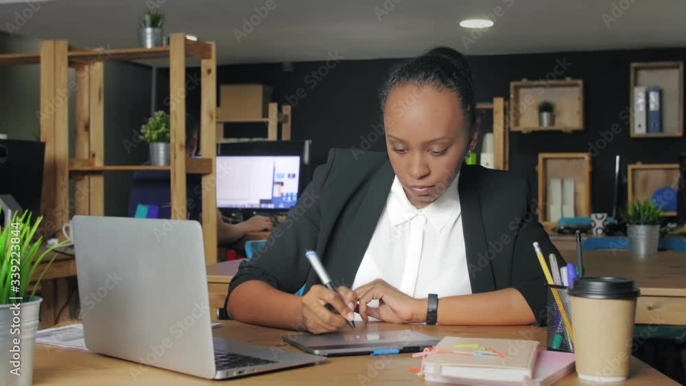 African american woman designer working at a laptop with a graphics tablet. African american woman designer working at a laptop with a graphics tablet.