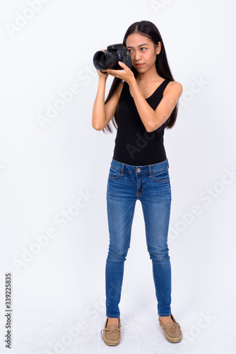 Full body shot of young Asian woman taking picture with camera
