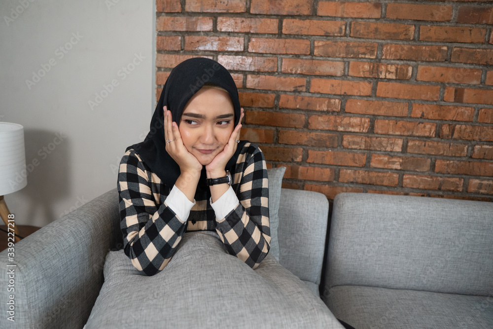 bored muslim woman sitting on a couch while stay home bored muslim woman sitting on a couch while stay home