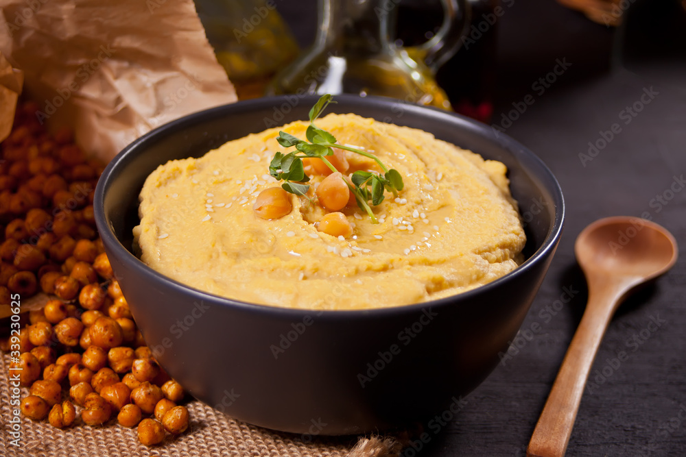 Traditional appetizer hummus with chickpea in a black bowl.