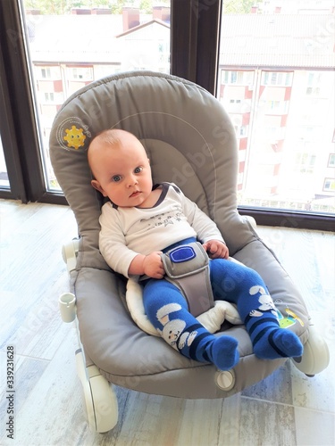 A small fair-skinned child / infant sits on a children's deck chair.