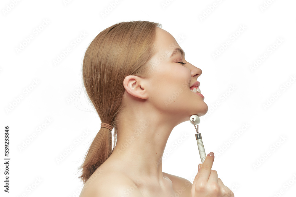 Beautiful girl makes a facial massage gua sha jade quartz roller, for the effect of skin rejuvenation. Procedure at home
