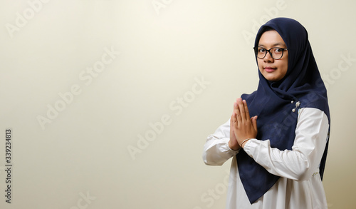Asian Muslim women wearing hijab gesturing to welcome guests