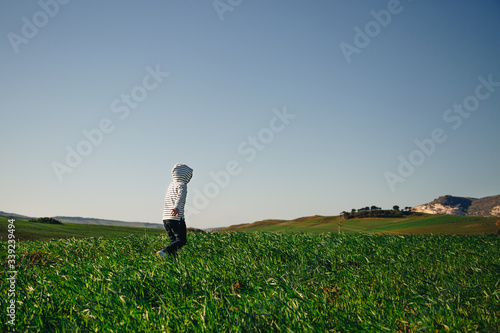 Hooded child runs free in the grass
