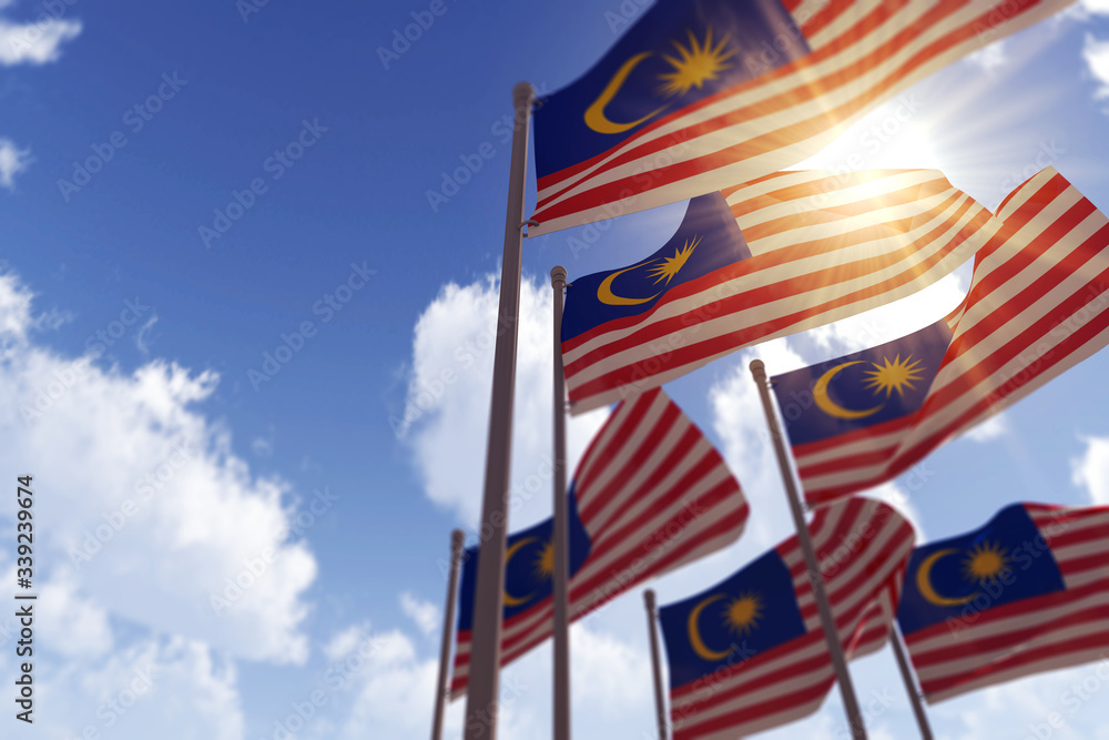 Malaysia flags waving in the wind against a blue sky. 3D Rendering