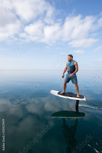 Canvas-taulu Man riding an electric hydrofoil foil board on a lake with a life jacket