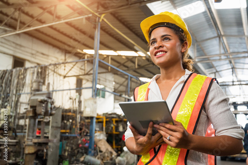 Female industrial worker working and checking machine in a large industrial factory with many equipment.