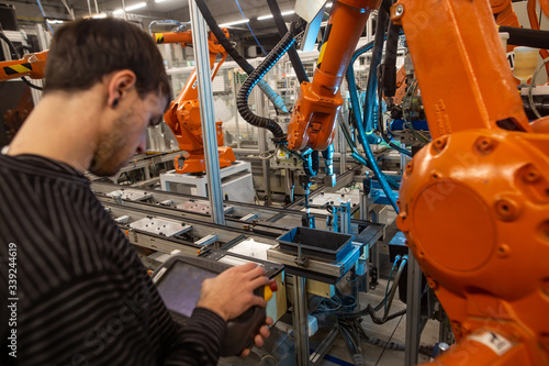 Repairman doing repair on automatic robot arms in huge automotive factory, industrial concept © Khaligo