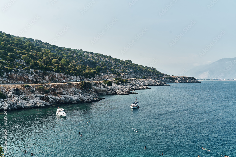 Brown rocks and sharp stones in the greenish blue water of Aegean sea near the shores of Demre city. Beautiful Turkish seascape. Travel concept. Water activity
