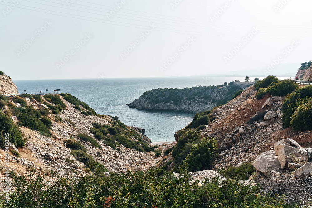 Fototapeta premium Brown rocks and sharp stones in the greenish blue water of Aegean sea near the shores of Demre city. Beautiful Turkish seascape. Travel concept. Water activity