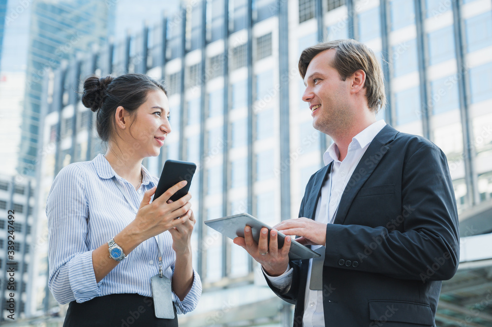 Portrait of businessman and woman using tablet and smartphone while standing on urban city background