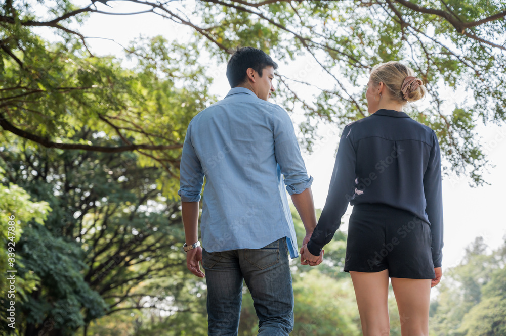 Young lovers walk hand in hand in the park Romanticly. On a relaxing holiday Young lovers walk hand in hand in the park Romanticly. On a relaxing holiday