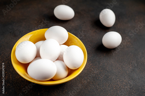 raw chicken eggs in a yellow mask on a stone background with copy space for your text